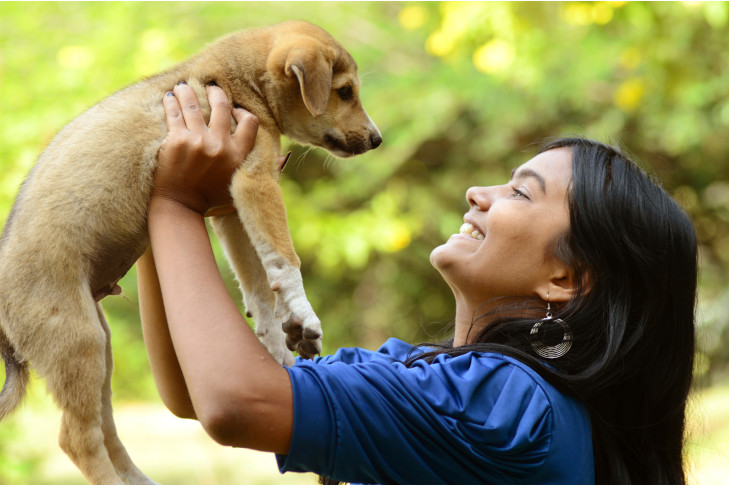 屋外で10代の少女が抱えている混合品種の子犬。